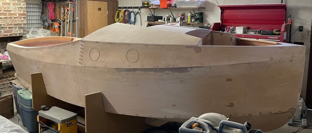 Exterior of a wooden boat build in progress in a garage.